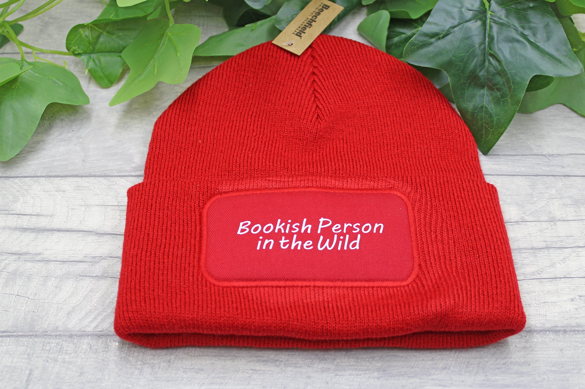 Flat lay of Bookish Person in the Wild beanie on rustic wood