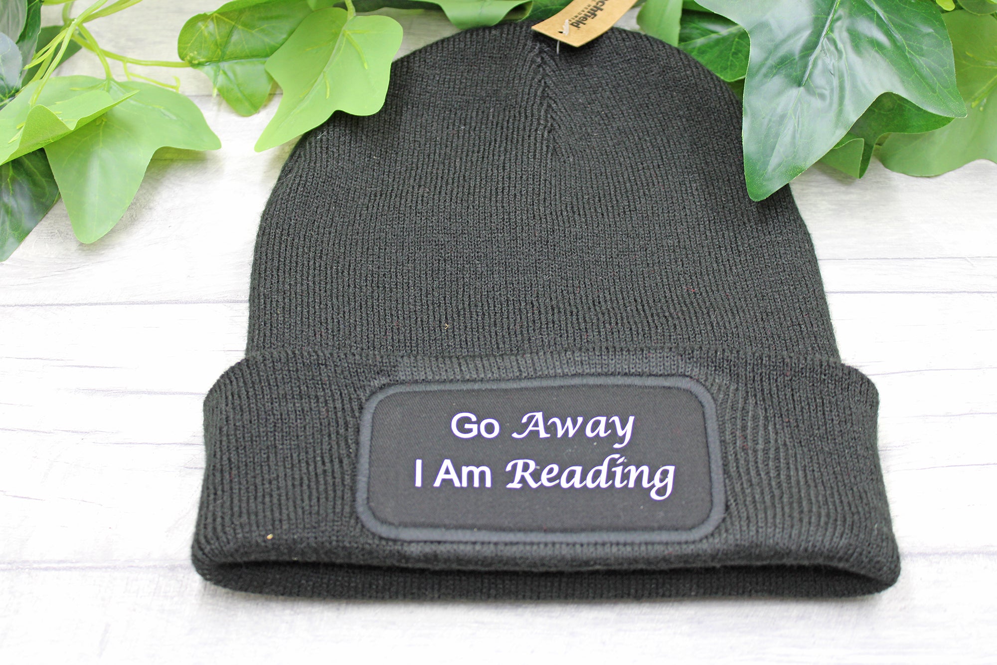 Flat lay of Go Away I Am Reading beanie