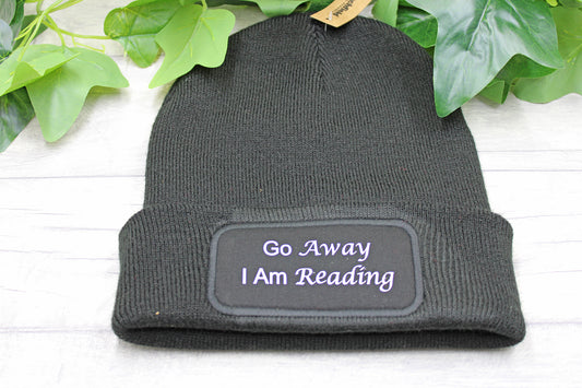 Flat lay of Go Away I Am Reading beanie